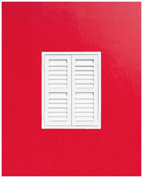 A minimalist white shuttered window centered on a