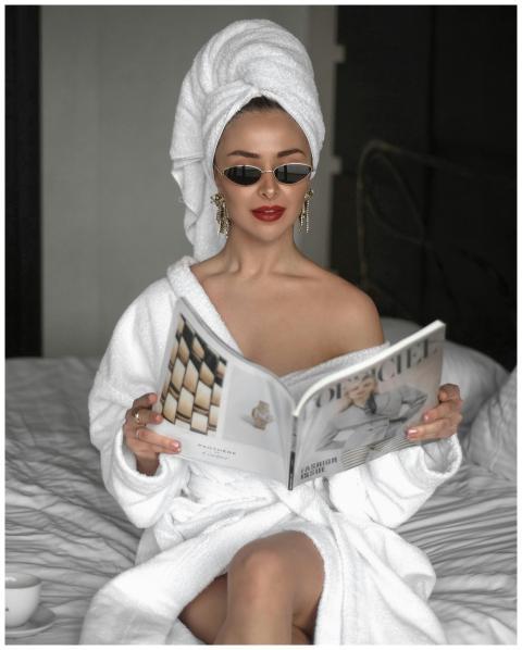 Elegant woman in bathrobe and sunglasses reads a m