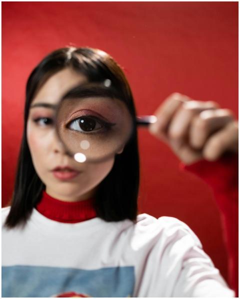 Creative portrait of a woman using a magnifying gl