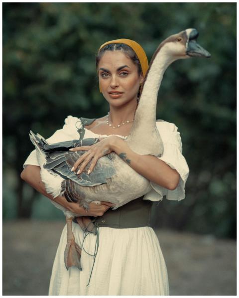 Portrait of a woman holding a goose outdoors, vint
