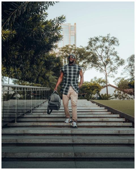 A stylish man in sunglasses descends stairs holdin