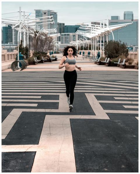 Woman in activewear jogging on a city path, showca