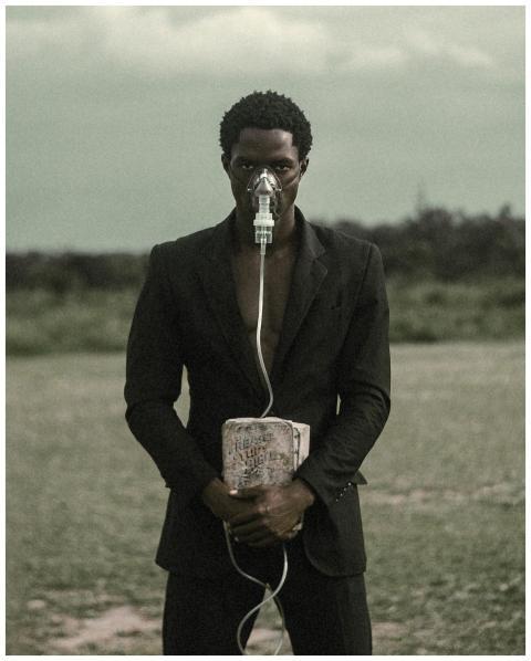 Man wearing suit with oxygen mask holds a block, s