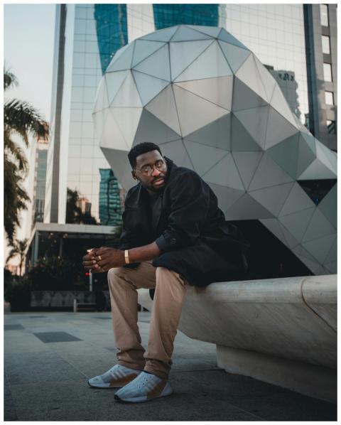 Man sitting outdoors in urban setting by modern ge