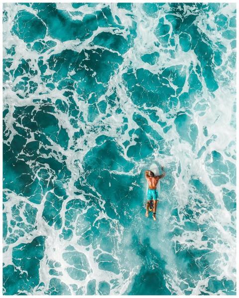 Dynamic aerial shot of a surfer enjoying turquoise