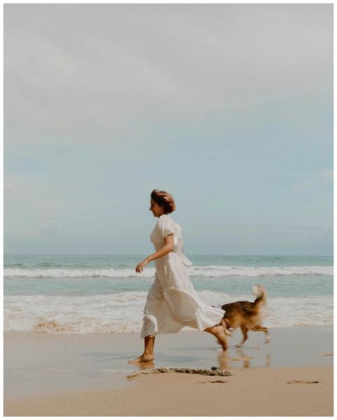 Carefree woman running with her dog along a sunny