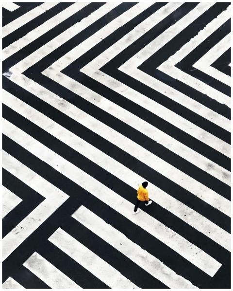 A person in a yellow jacket walks across a strikin