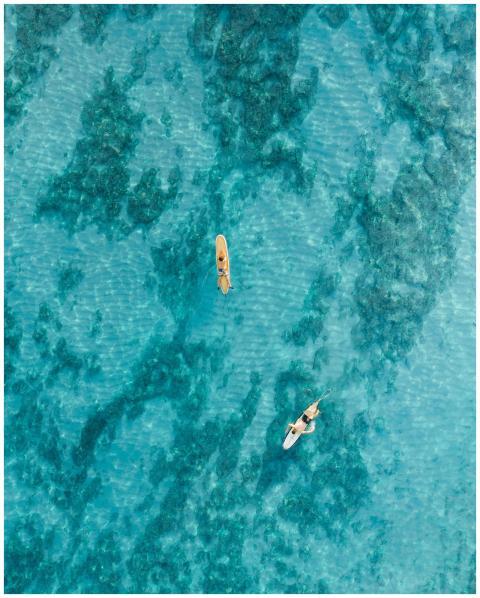 Aerial view of surfers on turquoise waters in Hawa