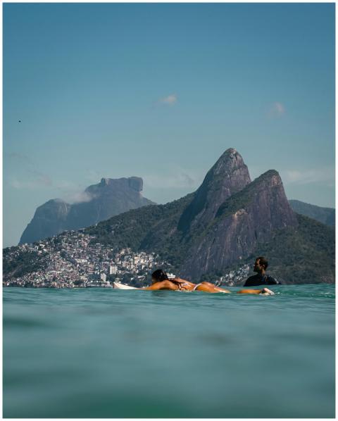 Surfers paddle on the waves with Rio de Janeiro's