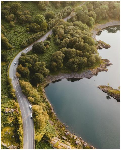 Aerial view of a winding road by a serene lake sur