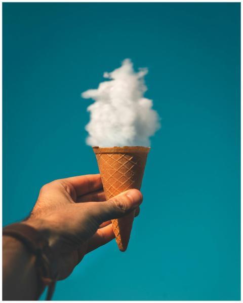 Hand holding an ice cream cone with a cloud effect