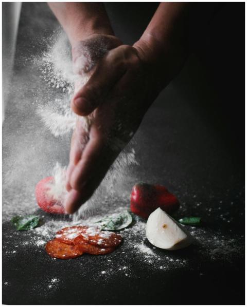 Hands clap flour over fresh vegetables and spices