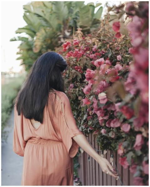 Woman in a pink dress walking beside vibrant bloom