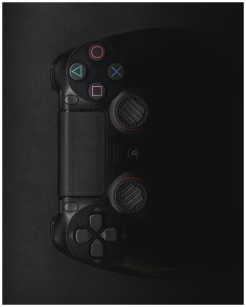 Moody close-up of a black gaming controller in low