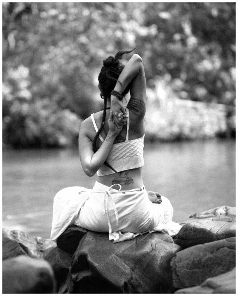 A woman practicing yoga near a river in a serene o