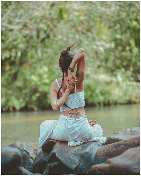 A woman in a yoga pose by a calm river, surrounded