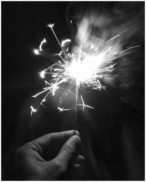 Close-up of a hand holding a sparkler, illuminatin