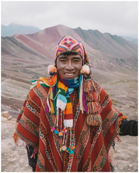 Man in colorful traditional wear in front of Peruv
