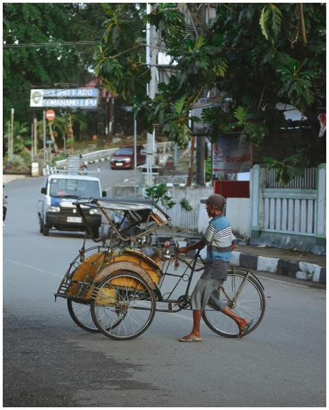Man pushing a traditional pedicab on an Indonesian
