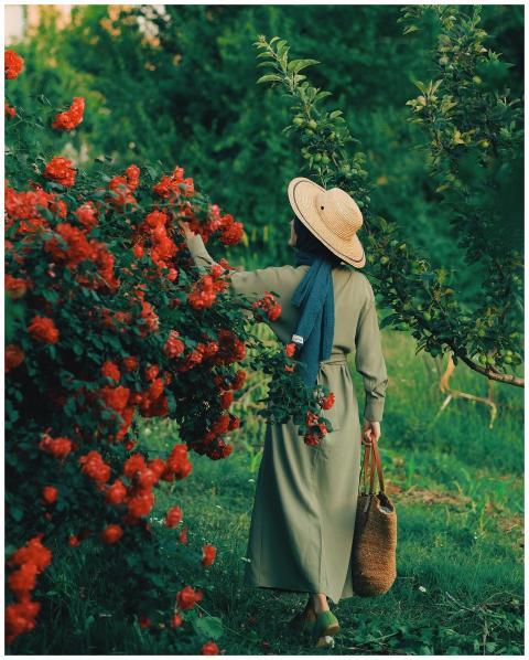 A woman in a green dress and straw hat explores a