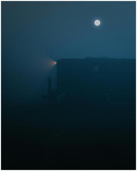 A cinematic night scene with a train under the moo