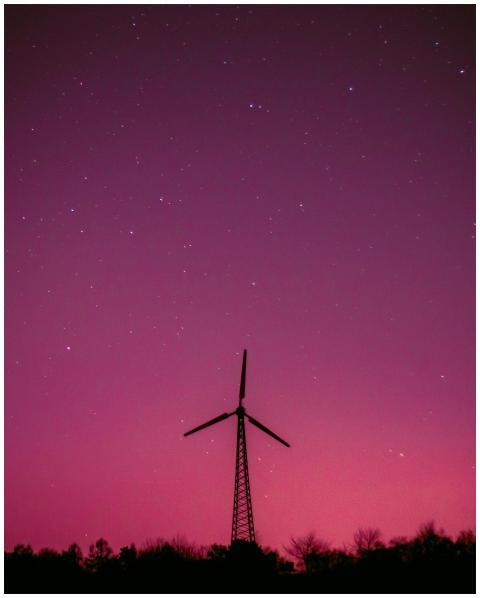 Wind turbine silhouette with a vibrant purple sky