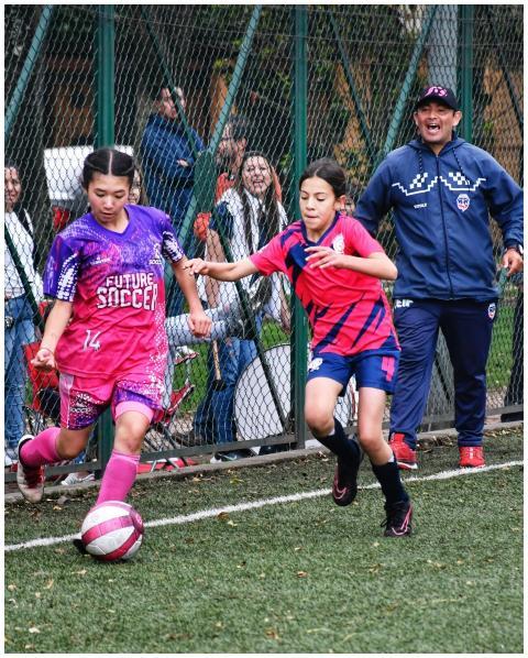 Two young girls playing football under the guidanc