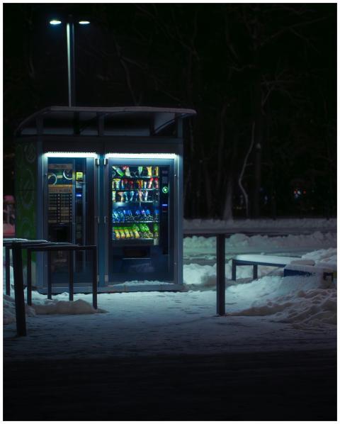 Vending machine illuminated at night in snowy Wroc