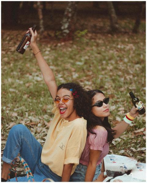Two women laughing and enjoying a picnic with beve