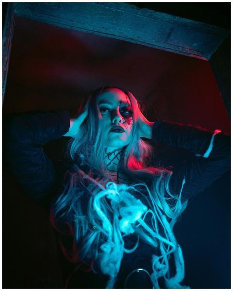 Portrait of a woman in spooky makeup under neon li