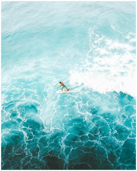 Stunning aerial shot of a surfer riding vibrant bl