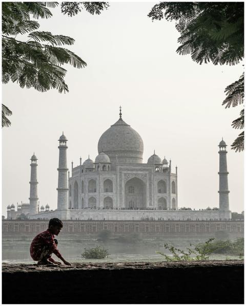 A child sits on a wall with the iconic Taj Mahal v