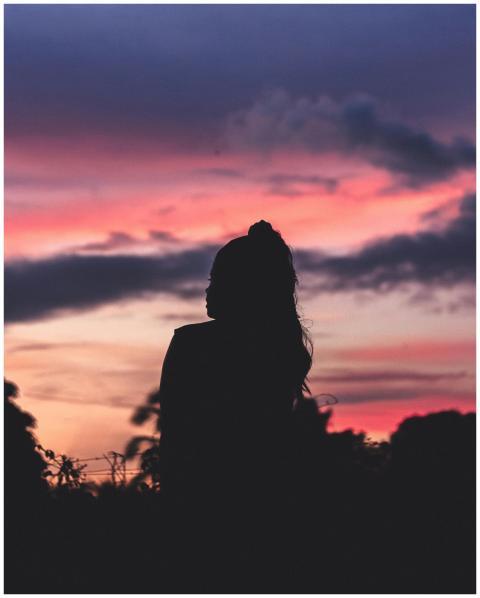 A woman silhouetted against a vivid sunset, blendi