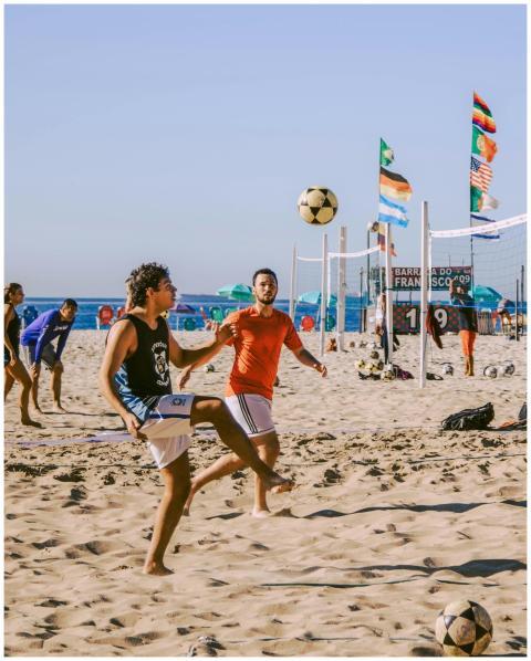 Group of young adults playing beach volleyball on