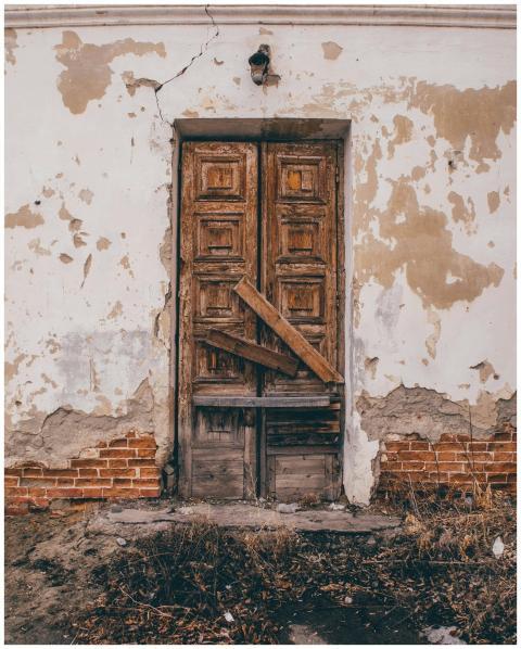Rustic wooden door on a cracked wall of an abandon