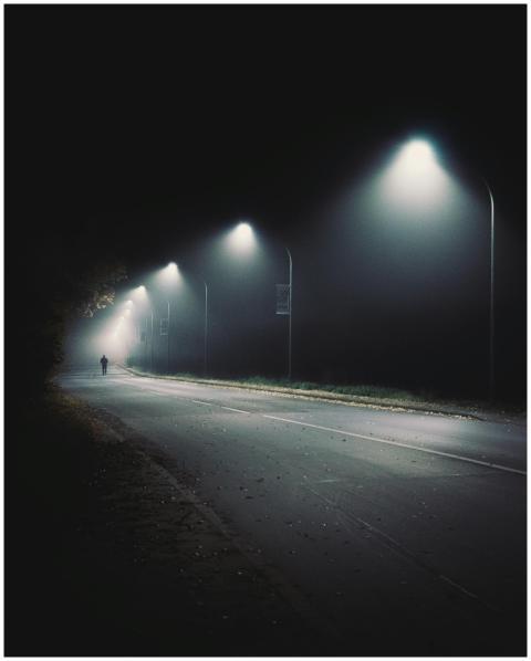 Silhouette of a person walking under streetlights