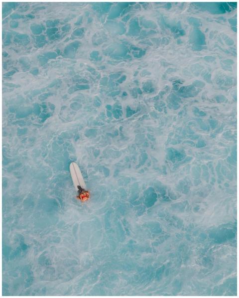 Aerial shot of a single surfer amidst turbulent oc
