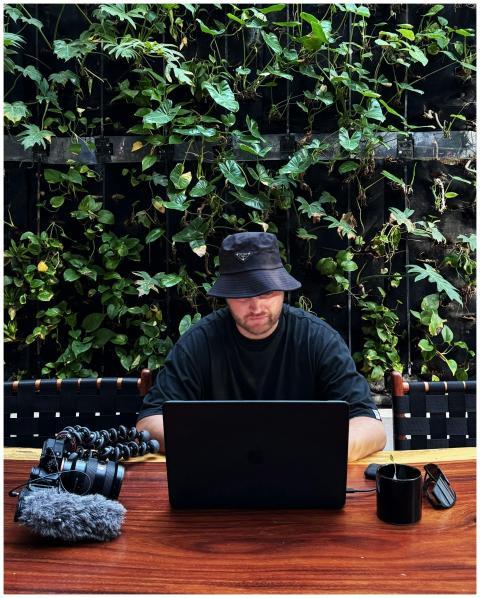 Man with laptop in outdoor café, surrounded by pla