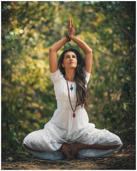 A woman meditating outdoors in a forest setting, e