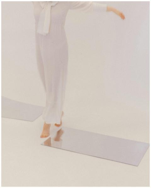 Artistic image of a woman in white balancing on re