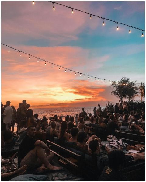 Crowd enjoying a stunning sunset at a Bali beach w