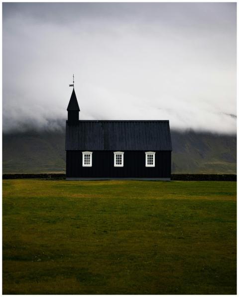 Stark black church against cloudy Icelandic landsc