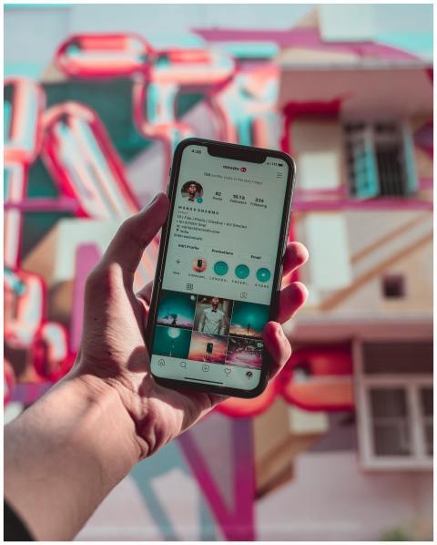 A hand holds a smartphone displaying social media,
