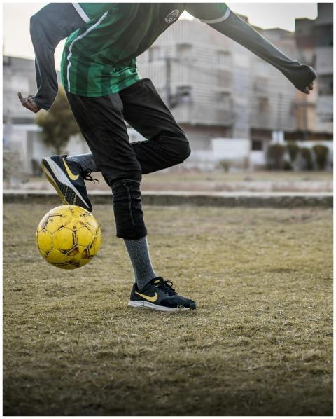 Teen kicking a soccer ball in an urban field, show