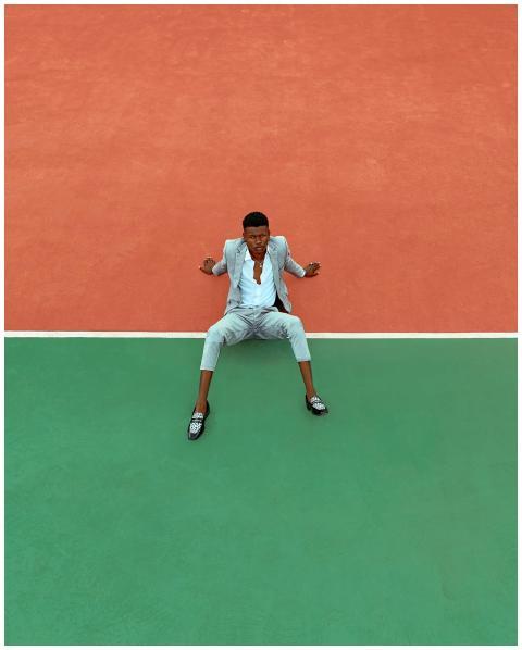 A fashionable man in a suit sits stylishly on a vi