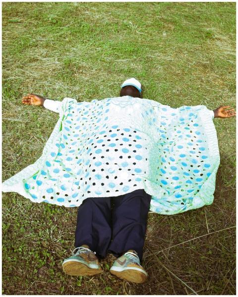 A person lies on the grass in vibrant traditional