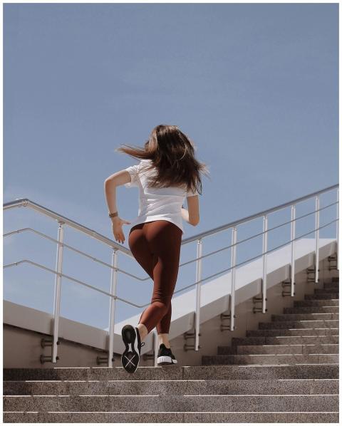 Fit woman in workout attire running up stairs on a