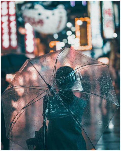 A person with an umbrella walks through a bustling