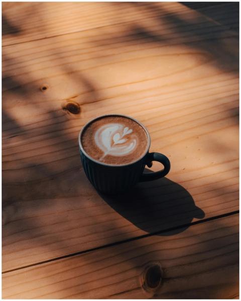A close-up of a coffee cup with latte art on a sun