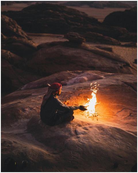 A serene scene of a man sitting by a campfire in t